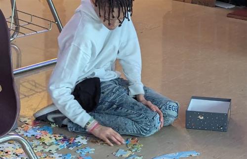 Male student sitting on the floor putting a puzzle together